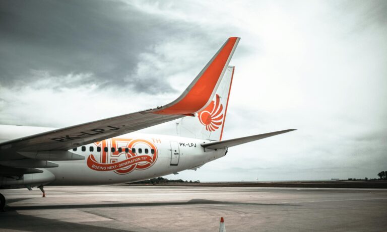 Close-up view of a Boeing 737 wing on the runway with a cloudy sky background.