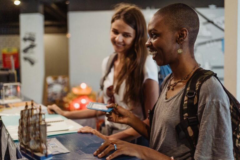 Two travelers check in at a hotel reception, smiling and engaging with the staff.